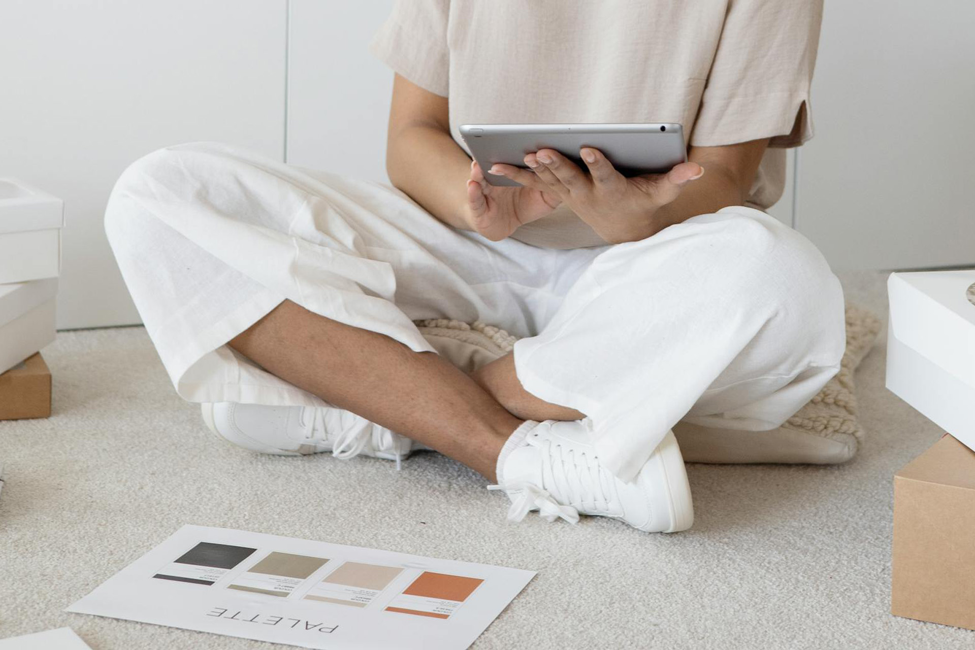 Femme assise par terre avec sa tablette dans les mains et une palette de couleurs