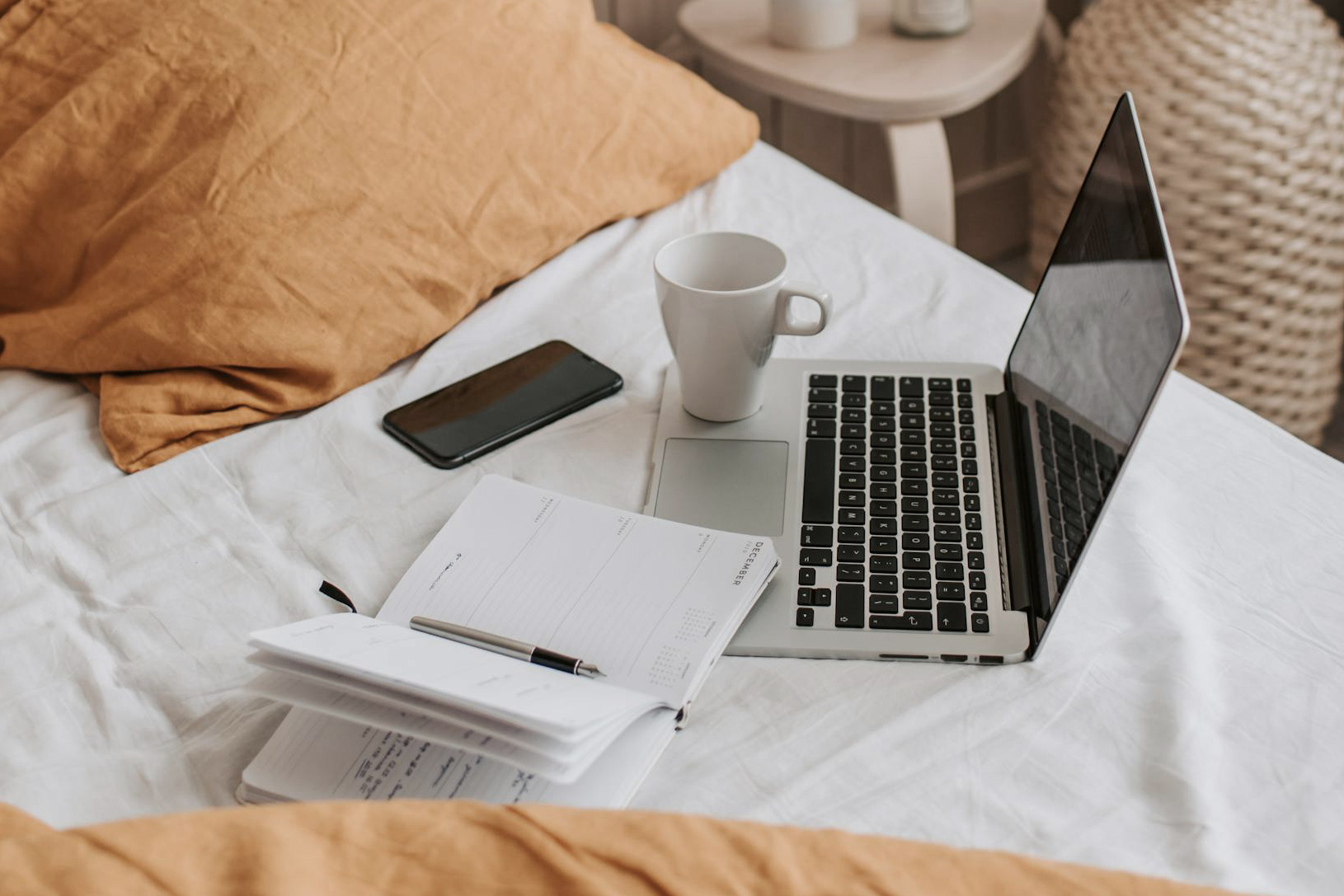 Ordinateur et carnet sur un lit avec une tasse de café
