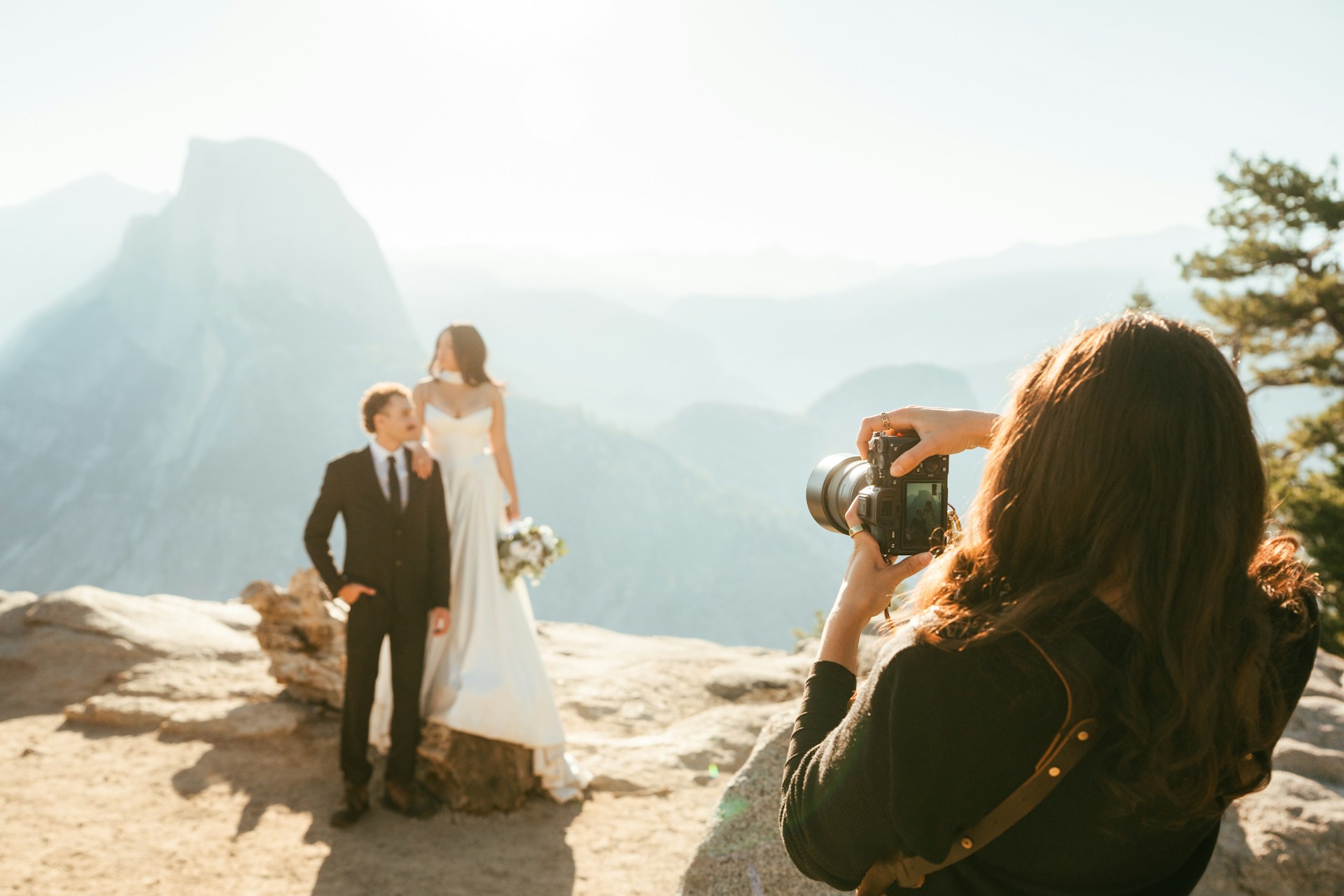 Photographe qui capture deux mariés devant des montagnes